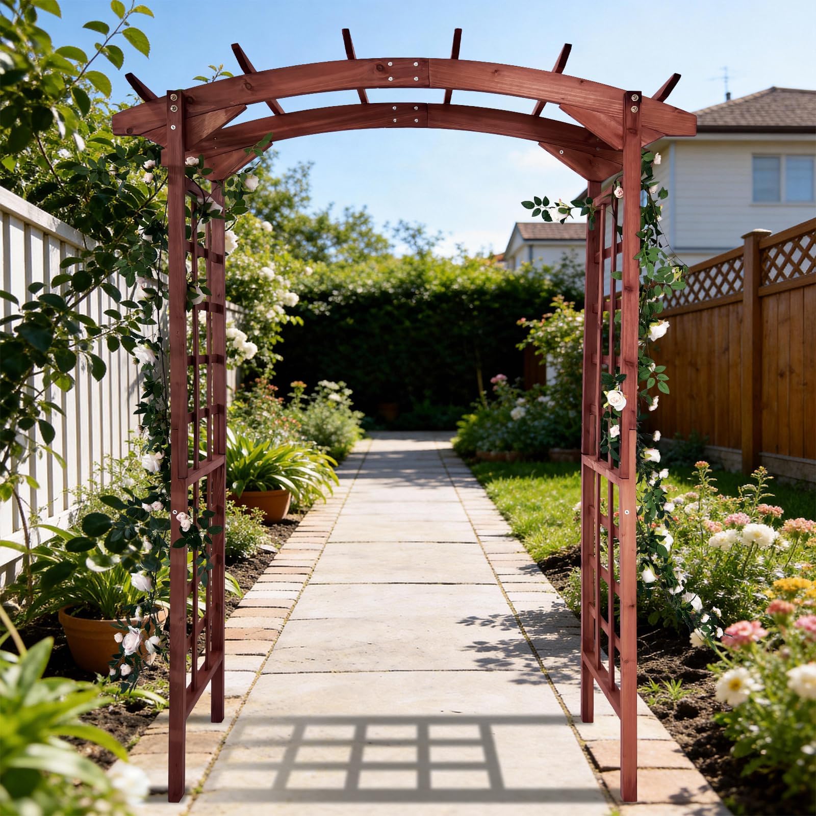 teak arched garden arbor covered with climbing flowers along a landscaped garden path
