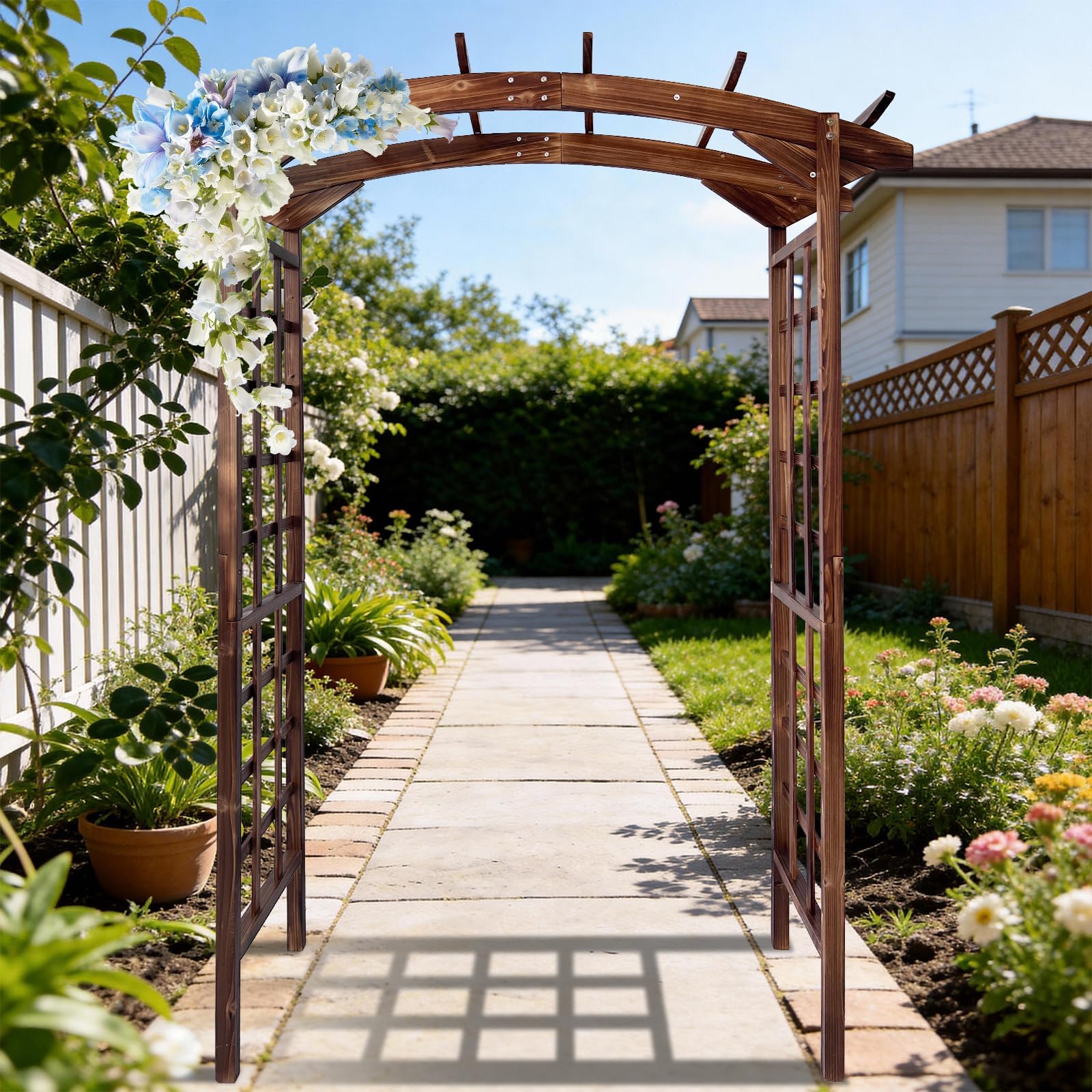 dark brown arched garden arbor covered with climbing flowers along a landscaped garden path